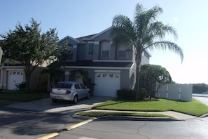 A two-story house with a garage, a parked car, and a palm tree. - Spacious 4-bedroom house in Orlando near airport (Orlando)
