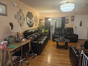 A living room with a sofa, chairs, a desk, and a coffee table. - Awesome 3-bedroom house with AC in Fort Washington near National Harbor & MGM (Fort Washington)
