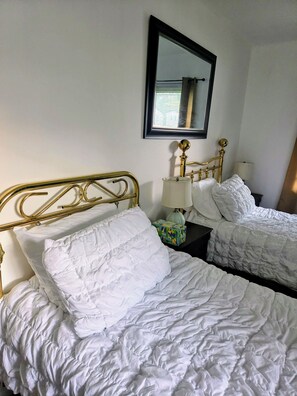 A hotel room with two single beds, a nightstand with a lamp, and a mirror on the wall. - Awesome 3-bedroom house with AC in Fort Washington near National Harbor & MGM (Fort Washington)
