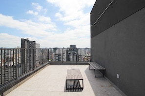 Eine Dachterrasse mit Metallgeländer, einer Bank und einem Tisch.