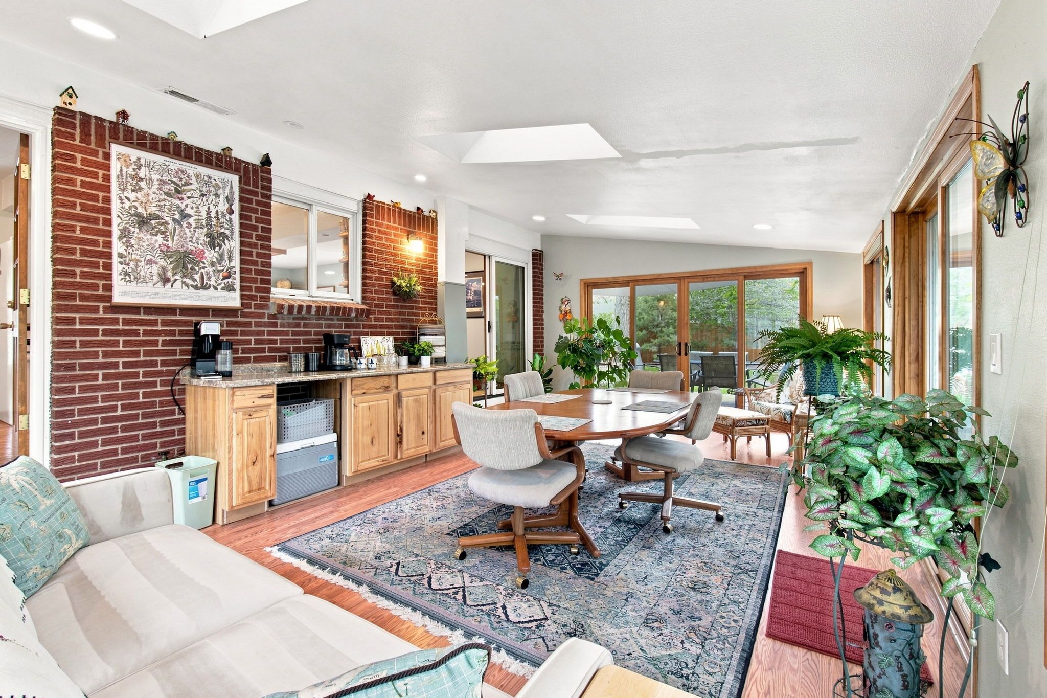 A modern kitchen with a brick wall, wooden cabinets, and a dining area with a table and chairs.