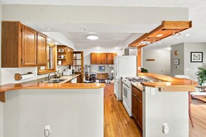 A kitchen with wooden cabinets, a central island, and a stove. - Relaxed 4BR Boulder Home Near CU & Mountains (Boulder)