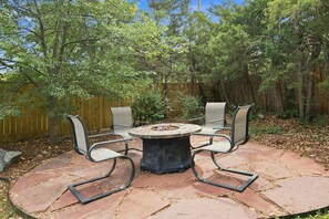 An outdoor patio with a round table and four chairs, surrounded by a wooden fence and trees. - Relaxed 4BR Boulder Home Near CU & Mountains (Boulder)