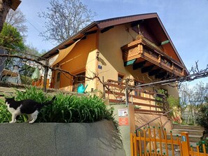 A two-story building with a balcony and a fenced area with plants.
