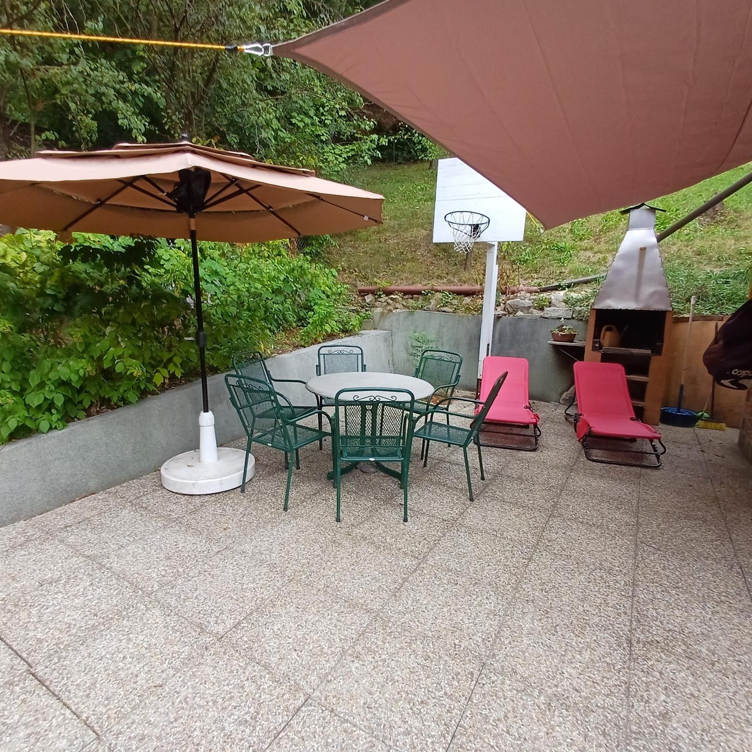 Une terrasse extérieure avec une table et des chaises, un panier de basketball et un barbecue.