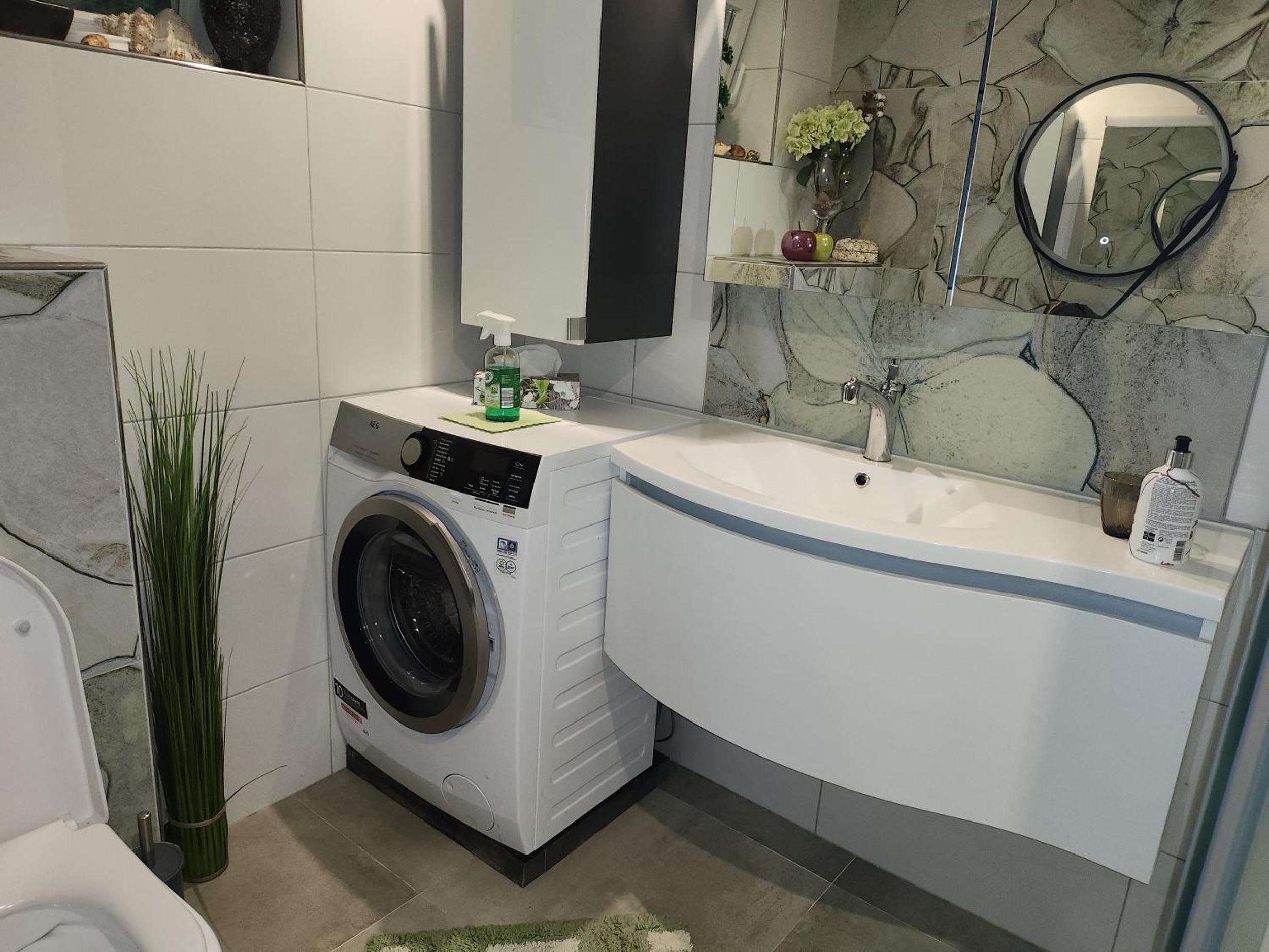 A modern bathroom with a built-in washing machine, a sink, and a mirror.