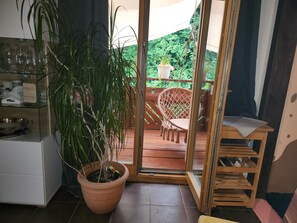 A room with a potted plant, a wicker chair, and a table with a placemat.