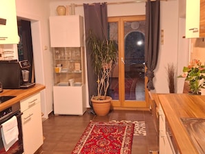 A compact kitchen with a coffee machine, a potted plant, and a sliding glass door leading to a balcony. - Apartment 'Naturparadies' with Mountain View, Balcony and Wi-Fi (Marktl)