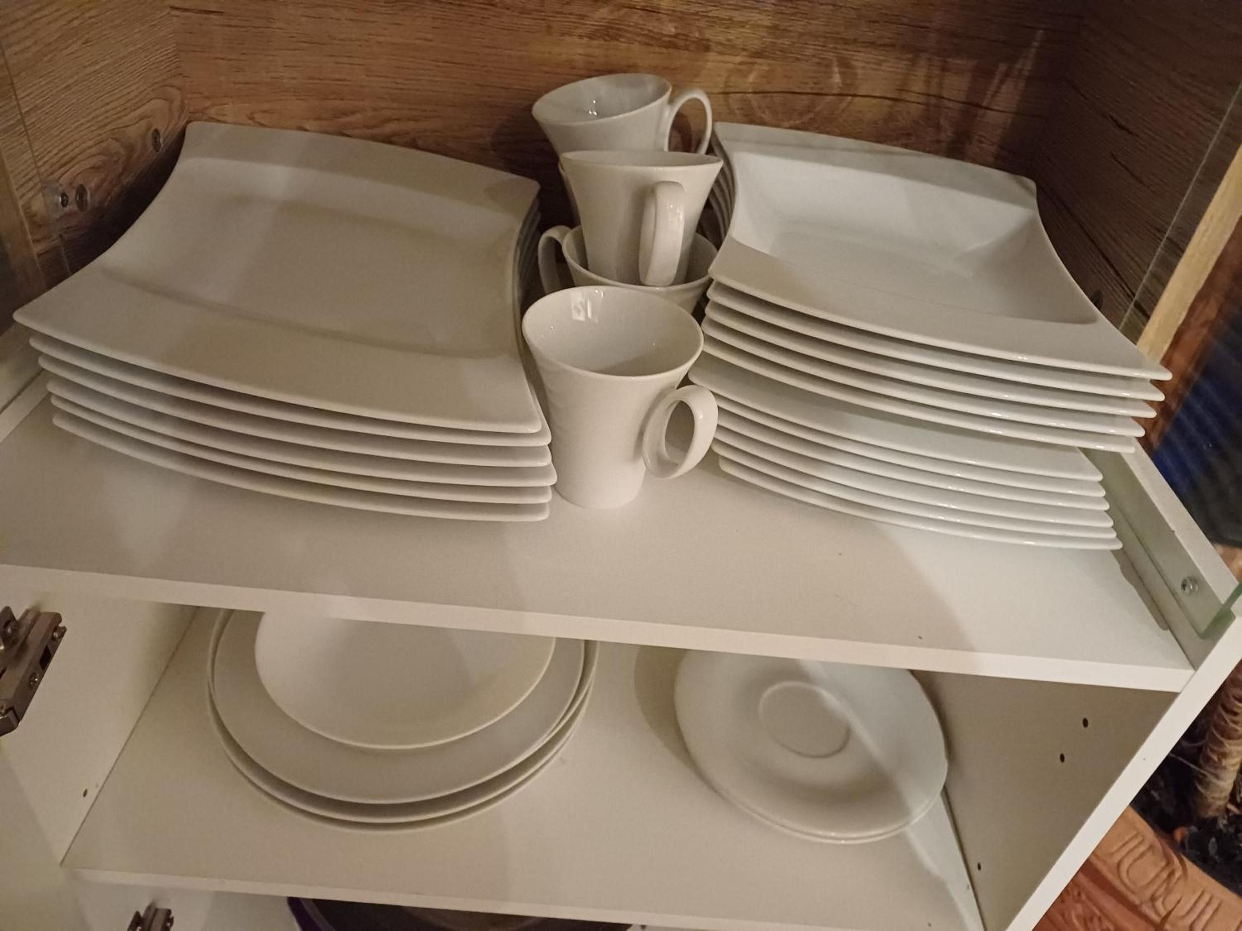 A storage unit with neatly stacked plates and cups.