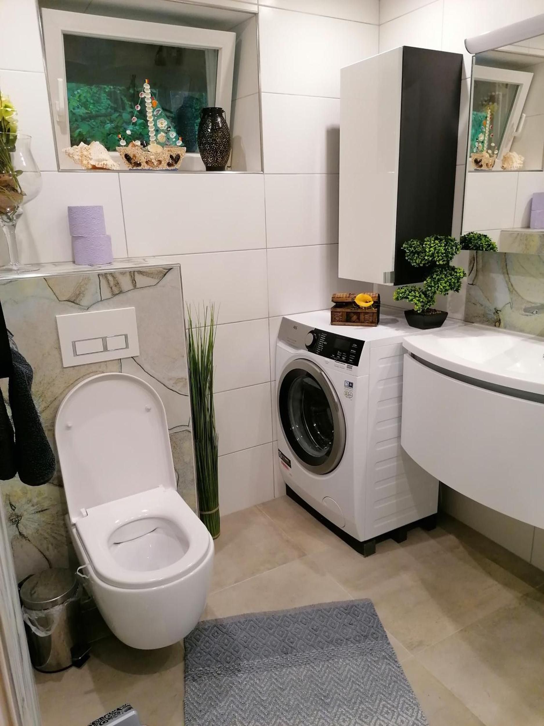 Ein kleines Badezimmer mit Toilette, Waschmaschine und Waschbecken.