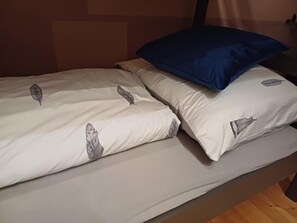 A single bed with a white mattress and pillows featuring a leaf pattern.
