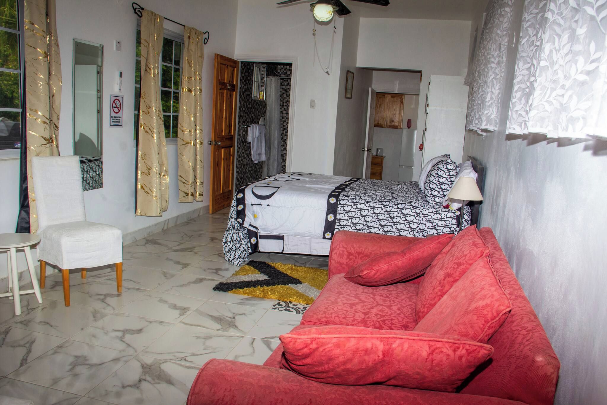 Un dormitorio con una cama, un sofá rojo, una silla y una pequeña mesa.