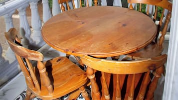 A covered outdoor seating area with a round wooden table and six chairs.
