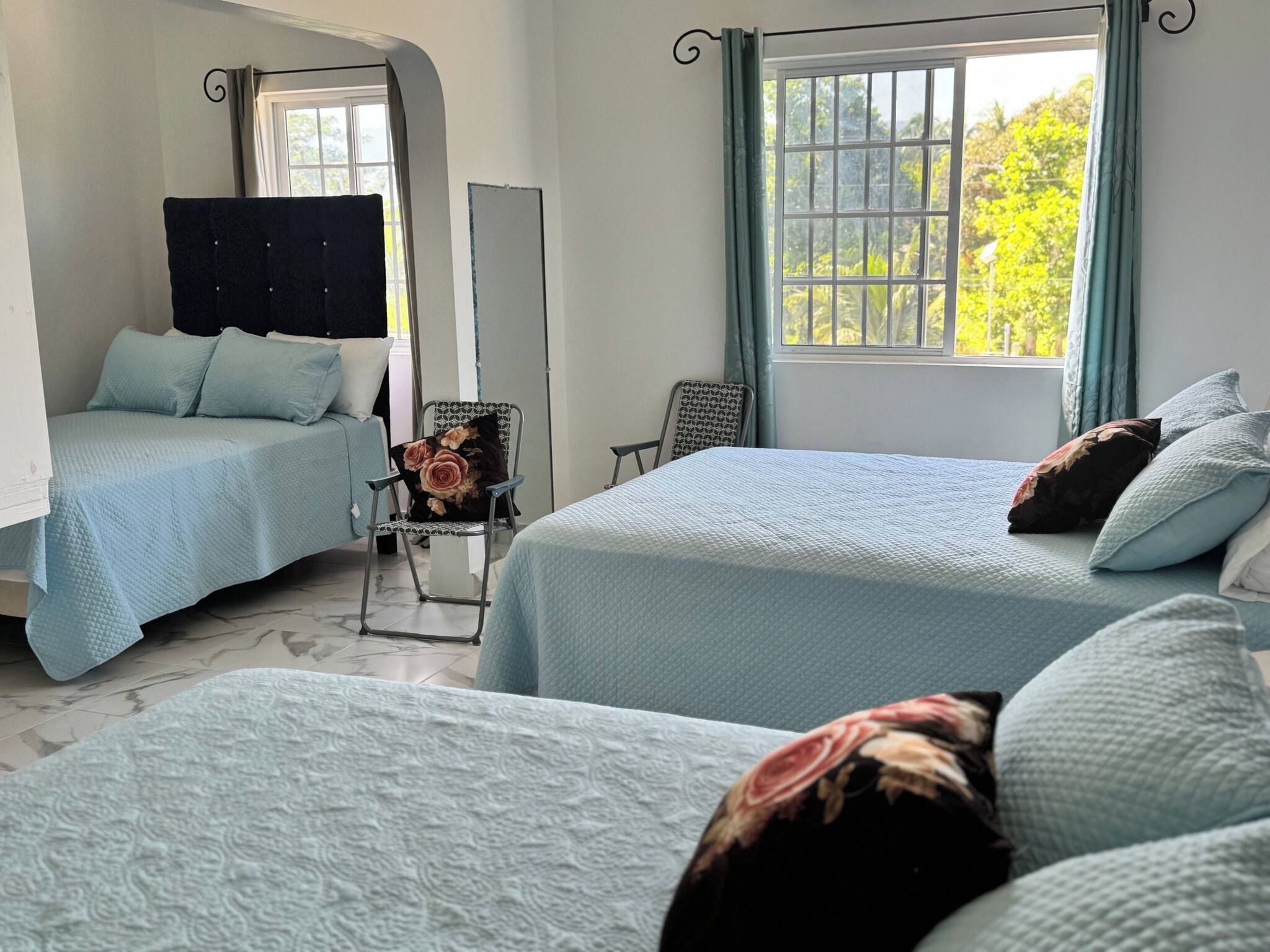 A hotel room with two beds, a chair, and a window with curtains.