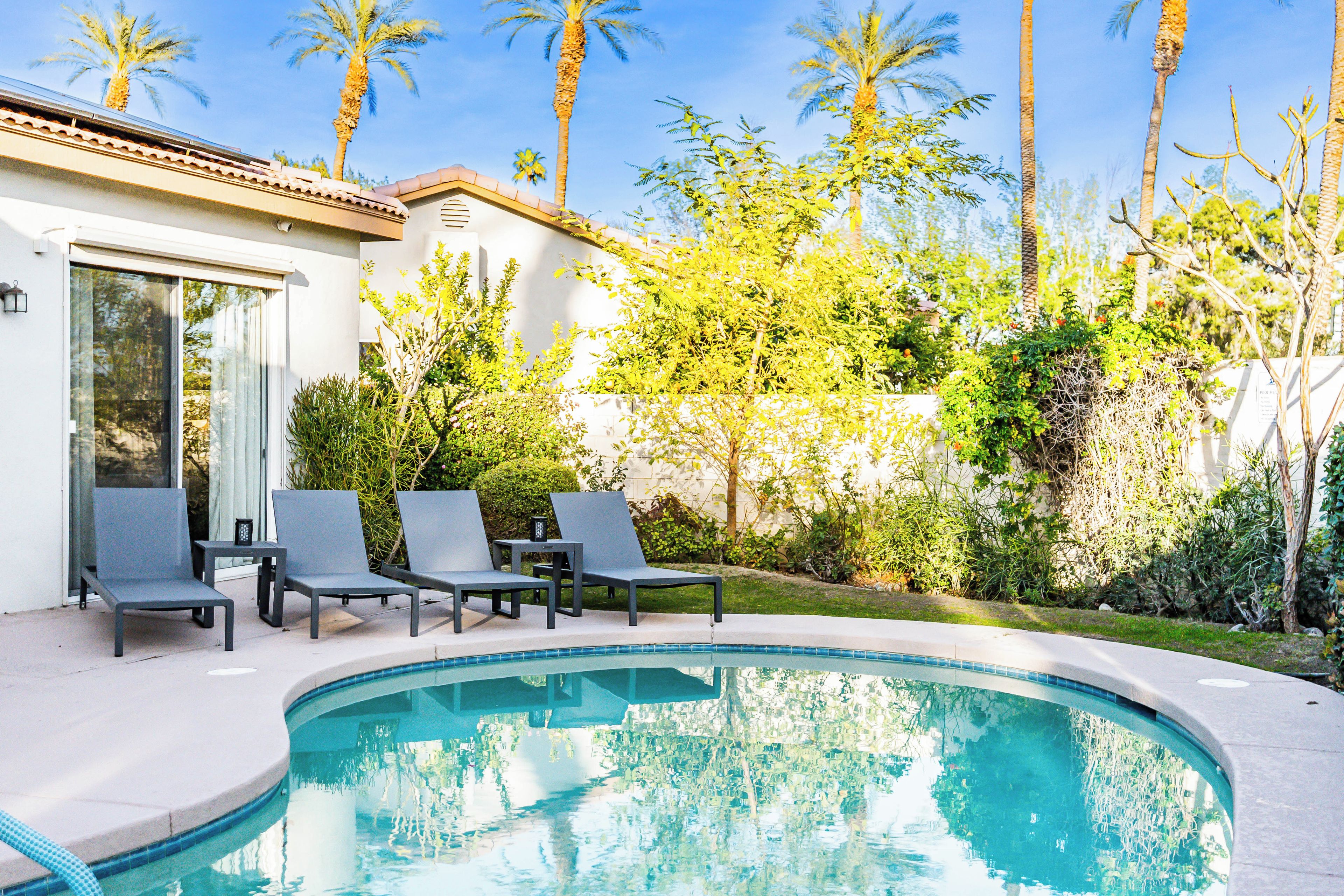 A swimming pool with lounge chairs and a glass door entrance.