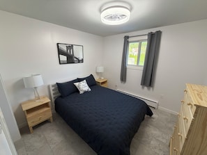 A bedroom with a bed, bedside tables, a nightstand, a window with curtains, a radiator, and a wooden dresser. - Newly remodeled 2-bedroom apartment in wonderful Johnstown / Richland Township (Johnstown)