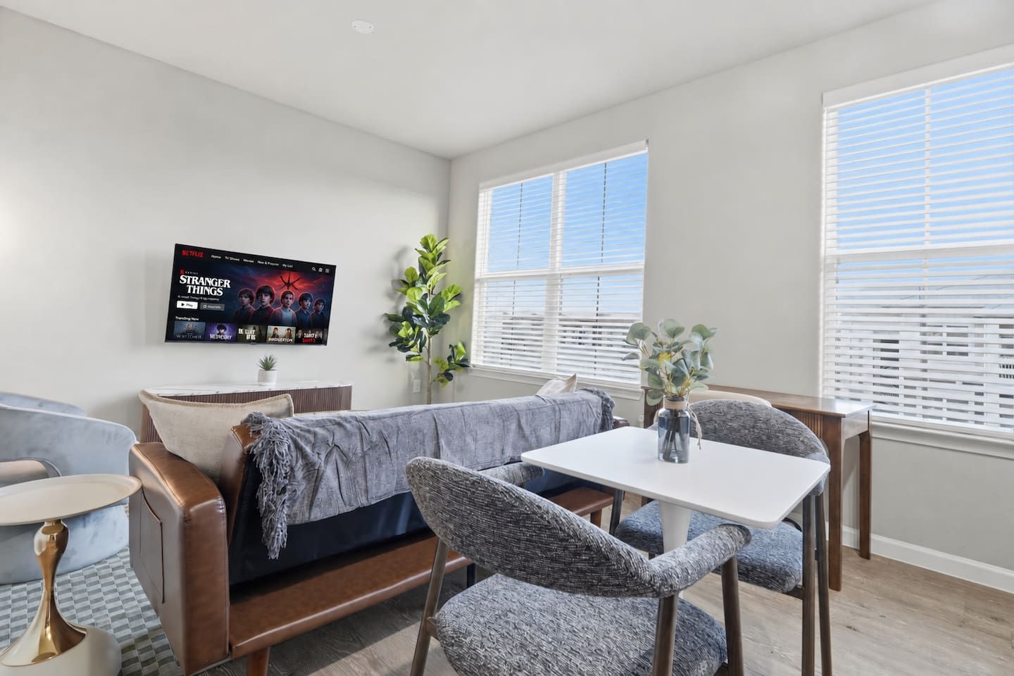 Una sala de estar moderna con un sofá modular, una mesa de comedor y un televisor de pantalla plana montado en la pared.