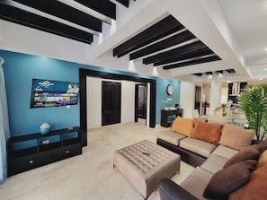 A modern living room with a flat-screen TV, a sofa set, a coffee table, and a large window. - Stunning Beachfront 2-bedroom Condo (Punta Cana)