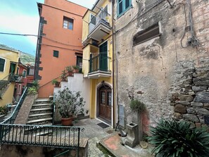 Un vialetto stretto con una scala che conduce a un edificio con una porta in legno e un piccolo balcone.