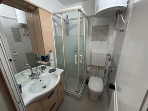 Un bagno con doccia vetrata, lavandino bianco e water.