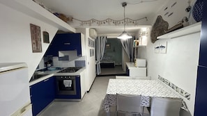 A compact kitchen with a dining area, featuring a stove, sink, and a table with chairs. - Pippo Cosy flat Central with A/C near beaches (Monterosso al Mare)