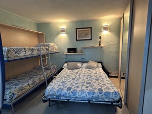 A dormitory room with bunk beds, a desk, and a wall-mounted shelf. - Pippo Cosy flat Central with A/C near beaches (Monterosso al Mare)