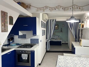 Una cucina compatta con mobili blu, un piano cottura a gas e un piccolo forno.