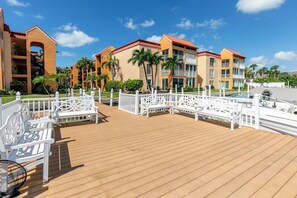 Ein Resort mit einer Holzterrasse, weißen Bänken und einem Poolbereich.