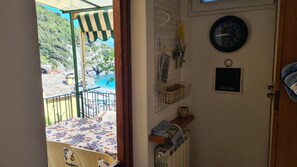 A room with a view of a coastal area, a clock, and a door with a towel hanging on it. - La Terrazza sul Mare Sea View - near best beaches (Monterosso al Mare)