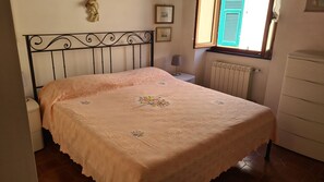A bedroom with a bed, a nightstand, a lamp, a radiator, and a dresser. - La Terrazza sul Mare Sea View - near best beaches (Monterosso al Mare)