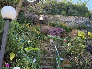A garden with a stone wall, various plants, and a metal railing. - La Terrazza sul Mare Sea View - near best beaches (Monterosso al Mare)