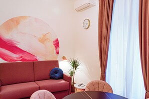 A modern living room with a red sofa, a round coffee table, and a large abstract painting on the wall. - Lele Rooms Vaticano (Roma)