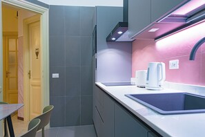 A modern kitchen with a built-in sink, two coffee makers, and a range hood. - Lele Rooms Vaticano (Roma)