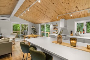 Una cocina moderna con una isla central, techo de madera y ventanas amplias.