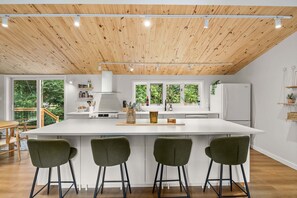 A modern kitchen with a large island, bar stools, and a view of the outdoors.