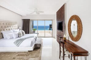 Ein Hotelzimmer mit Bett, Fernseher, Schreibtisch und einem großen Fenster mit Blick auf das Meer.