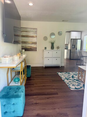 A modern kitchen with white cabinets, a stainless steel refrigerator, and a dining area with a white table and chairs. - Newly renovated custom 3-bedroom/ 2 bath house in coastal area! (West Palm Beach)