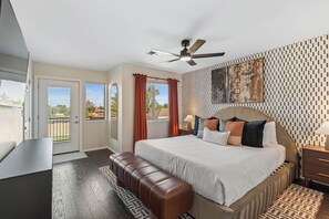A modern hotel room with a large bed, a ceiling fan, a view through the door, and a patterned wall. - Mesa Resort • 6BR • Pool + Slide • Spa • Pickleball • Theater (Mesa)