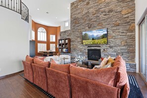 Ein Wohnzimmer mit Steinwand, Kamin, Fernseher und einer Couch.