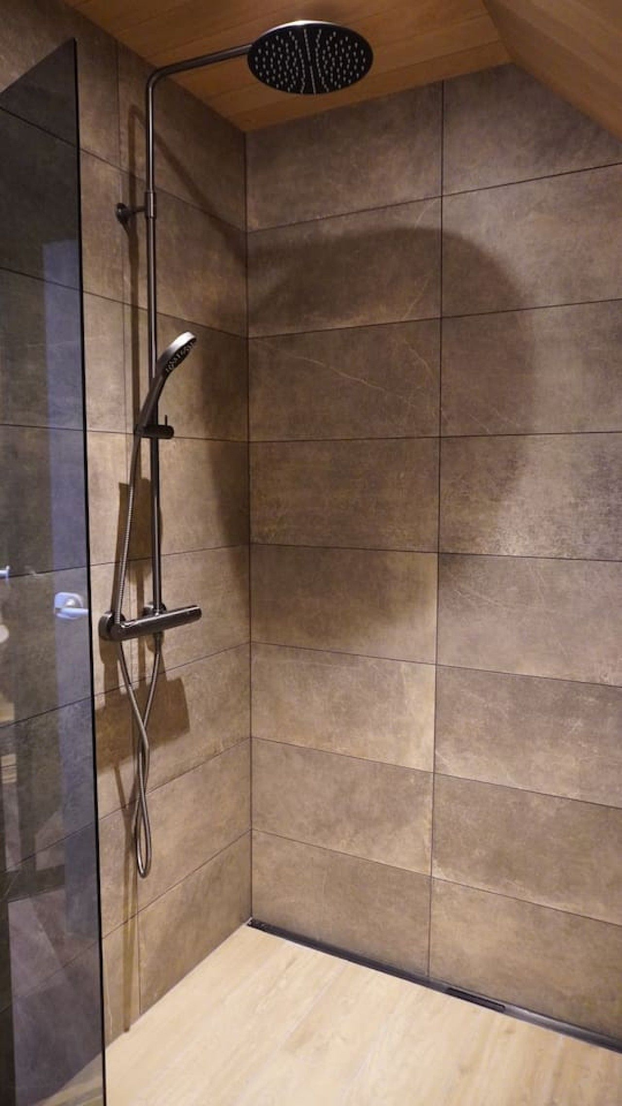 A shower with a handheld showerhead and a wall-mounted faucet.