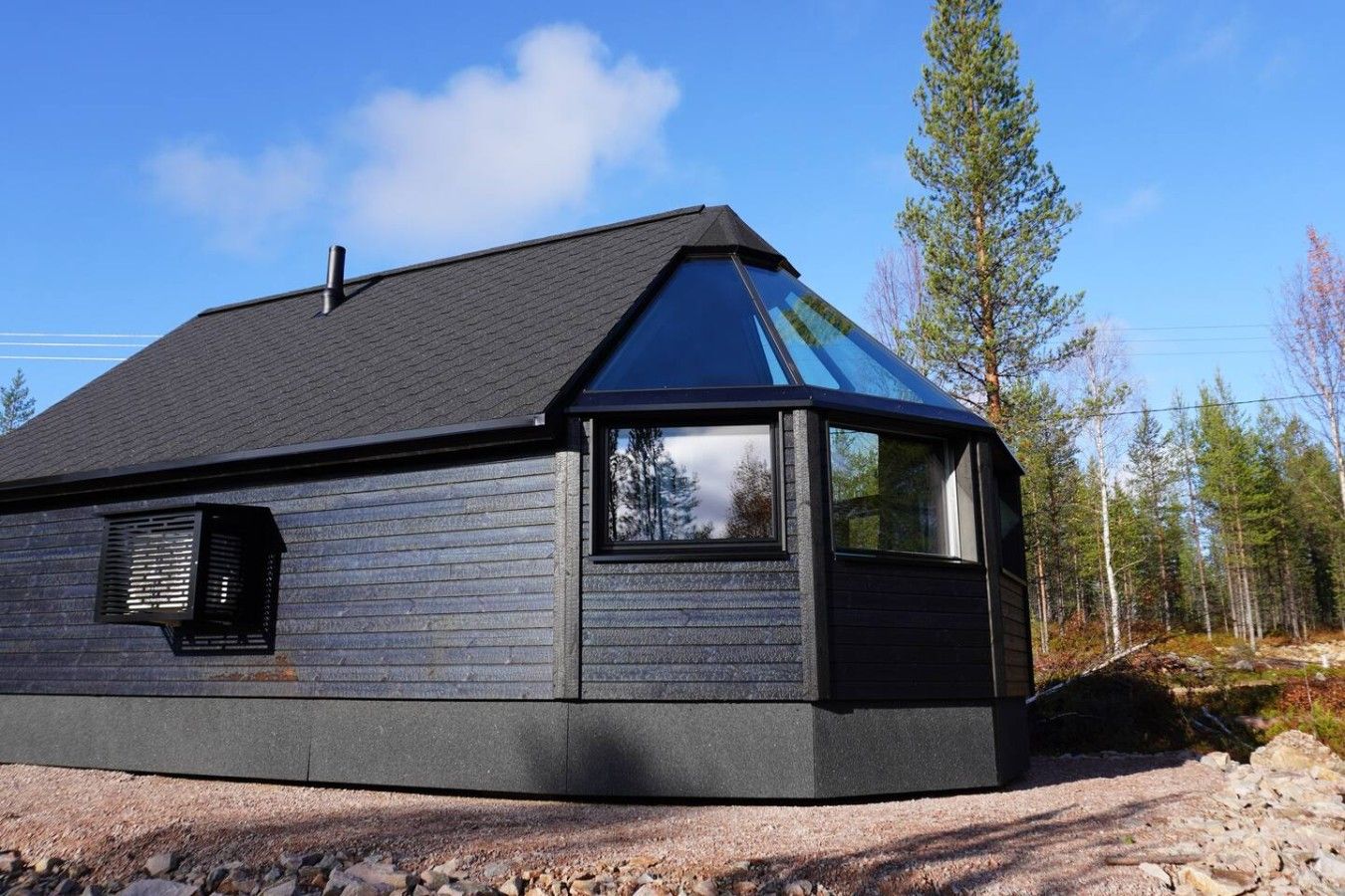 A modern, single-story building with a sloped roof, large windows, and a visible chimney.