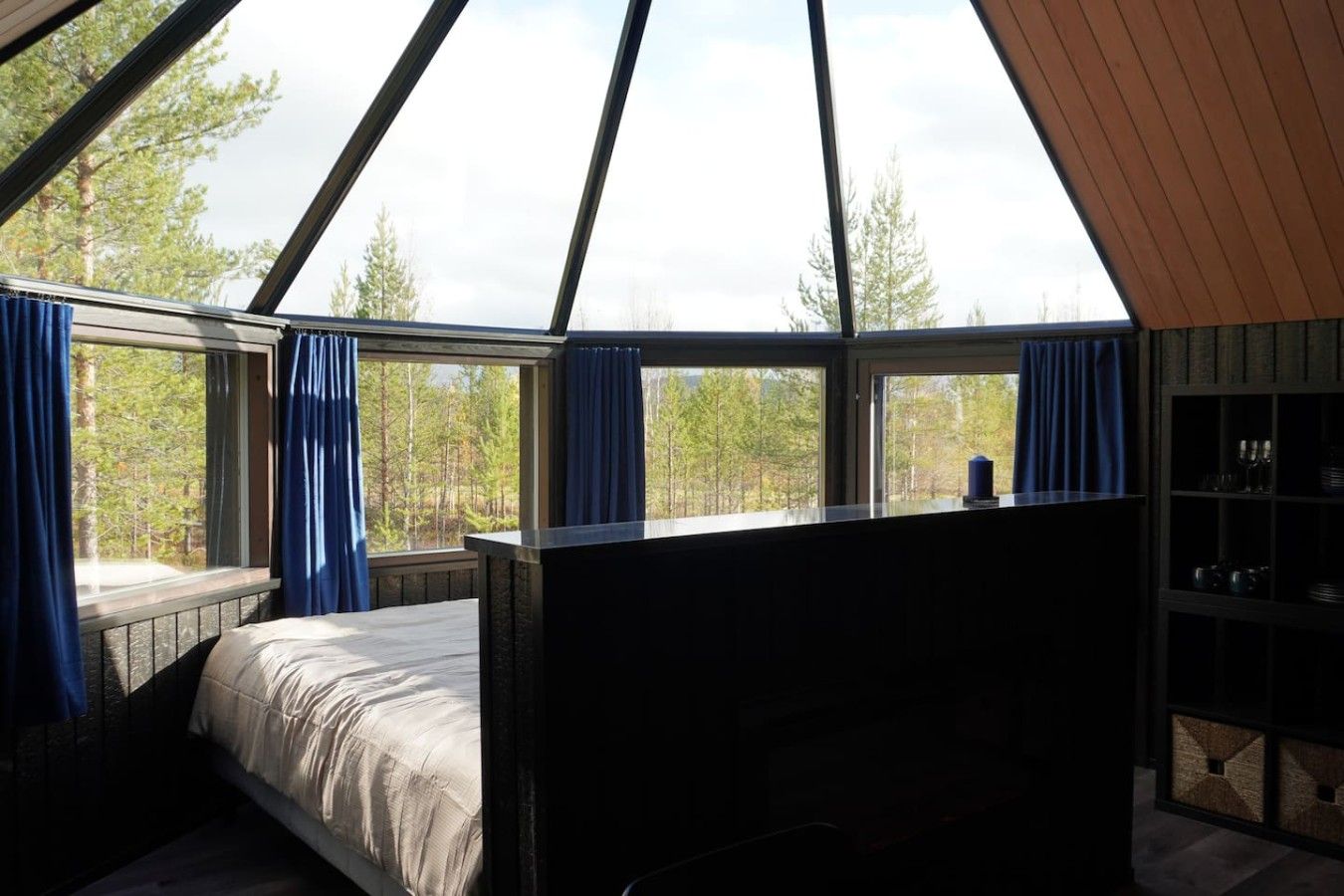 A bedroom with a bed, a window with curtains, and a view of trees.