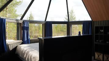 A bedroom with a bed, a window with curtains, and a view of trees.