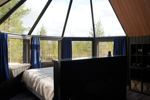 A bedroom with a bed, a window with curtains, and a view of trees.