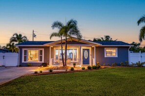 A single-story house with a front porch, a garage, and a well-maintained lawn. - St Pete Poolside Paradise w/ Outdoor Bar (St. Petersburg)