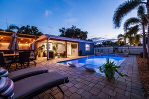 A backyard with a swimming pool, outdoor seating, and a covered patio area. - St Pete Poolside Paradise w/ Outdoor Bar (St. Petersburg)