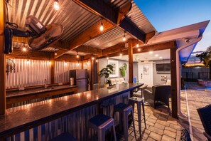 A covered outdoor bar area with a counter, stools, and a grill. - St Pete Poolside Paradise w/ Outdoor Bar (St. Petersburg)