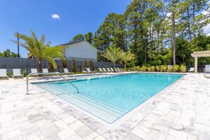 A rectangular swimming pool with a tiled deck, surrounded by lounge chairs and palm trees. - PCB Family Getaway, 3BR Townhome, Sleeps 6 - Community Pool (Panama City Beach)