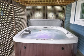 Ein Whirlpool mit Holzverkleidung, umgeben von einem Gitterzaun.