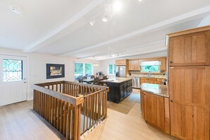 A spacious kitchen with wooden cabinets, a central island, and a dining area with chairs. - New Rental! Relaxing 3-bedroom Lake Wawasee channel home in Johnson's Bay (Syracuse)